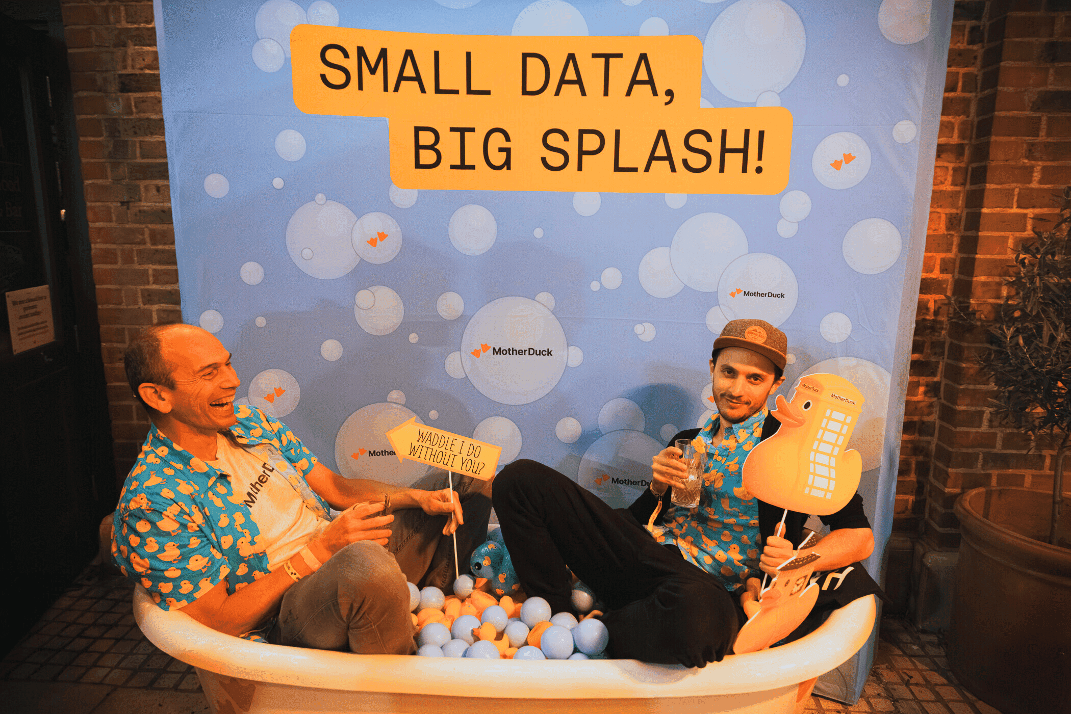 Two men in Hawaiian shirts in a bathtub of balls with 'Small Data, Big Splash!' backdrop.